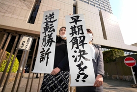旧優生保護法訴訟の控訴審判決を受け、東京高裁前で「逆転勝訴」などと書かれた紙を掲げる弁護士＝１１日午後２時４分