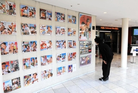 神戸国際松竹の玄関前で寅さんシリーズのポスターに見入る観客＝神戸市中央区御幸通８