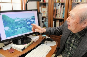 出身地、択捉島蘂取村の当時の写真を見つめる山本忠平さん。現在は草むらになってしまっている＝神戸市中央区