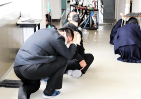 大掃除中に放送が流れ、その場で頭を守る生徒ら＝２２日、兵庫県立舞子高校