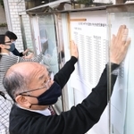 合格者の番号を張り出す大学職員＝７日午前、神戸市西区学園東町９、神戸市外国語大学（撮影・坂井萌香）