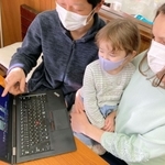 ウクライナの故郷を訪れたときの写真を娘と一緒に見る川瀬イダさん（右）と夫の弓弦さん＝神戸市垂水区大町３
