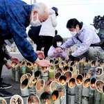 兵庫から運んだ竹灯籠に火をともす参加者＝１１日午後２時３５分、宮城県名取市閖上東