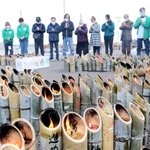 竹灯籠を囲み、黙とうをささげる兵庫のボランティアや近隣住民ら＝１１日午後、宮城県名取市閖上東