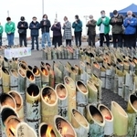 竹灯籠を囲み、黙とうをささげる兵庫のボランティアや近隣住民ら＝１１日午後、宮城県名取市閖上東
