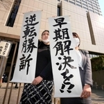 旧優生保護法訴訟の控訴審判決を受け、東京高裁前で「逆転勝訴」などと書かれた紙を掲げる弁護士＝１１日午後２時４分