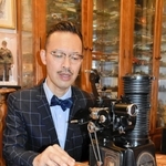 岡部芳郎さんの数少ない遺品である映写機とフィルムを手に、足跡を語る孫の芳彦さん＝神戸市灘区