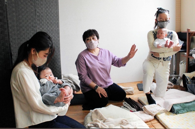 辻直美さん（中央）の指導の下、「まぁるい抱っこ」を実践する２組の母子＝大阪府島本町広瀬４