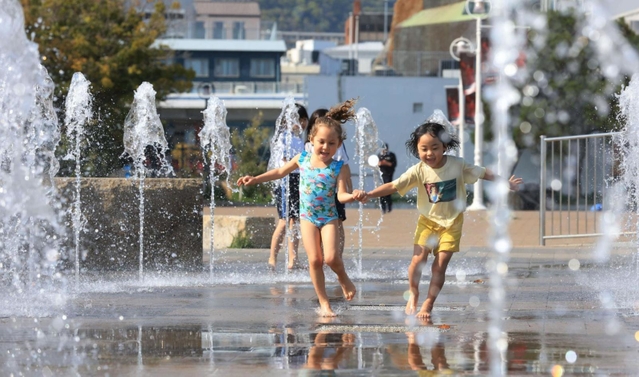 神戸は今年初めての「夏日」。水遊びをする子どもたち＝１３日午後、神戸市中央区波止場町