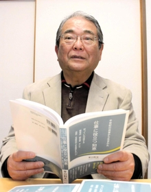 「反省が執筆のきっかけ」と著書を手にする早川利文さん＝明石市内