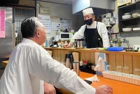 カウンター越しに常連客との会話が弾む石川博純さん（右）＝年金食堂
