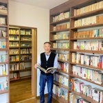 壁一面に収められた本に囲まれ、オープンを心待ちにする福井正敏さん＝姫路市伊伝居