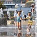 神戸は今年初めての「夏日」。水遊びをする子どもたち＝１３日午後、神戸市中央区波止場町