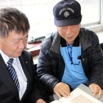 赤穂軟式野球協会の選手成績を集めたスクラップブックを手にする永安弘理事長（右）ら＝赤穂市加里屋