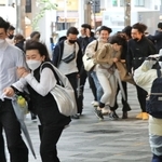 ゴールデンウイークの初日、神戸・三宮の繁華街では傘を手にした若者らを猛烈な風が襲った＝２９日午後、神戸市中央区加納町４（撮影・鈴木雅之）
