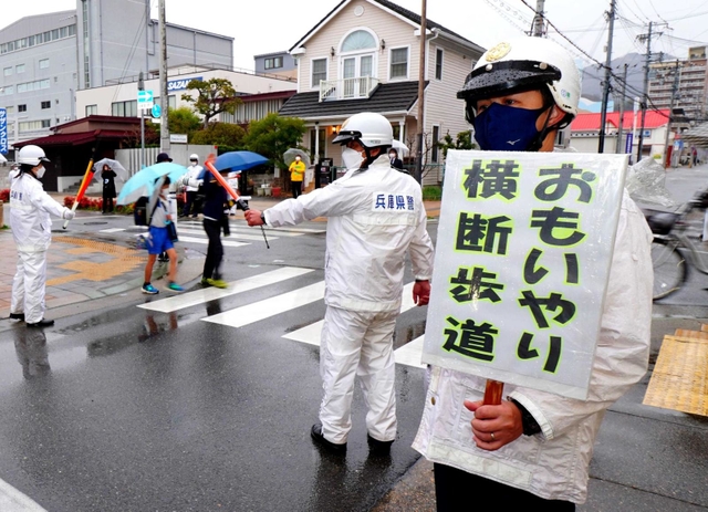 兵庫県警が指定した「おもいやり横断歩道」で横断歩道の歩行者優先を呼び掛ける警察官ら＝３月１８日、神戸市長田区細田町３