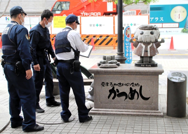 壊された「かっつん」のモニュメントを調べる加古川署員ら＝９日、加古川市加古川町寺家町、ベルデモール商店街