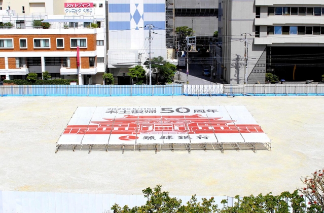 沖縄都市モノレールの駅から見えるよう、琉球銀行の敷地内に設置された復帰５０年記念の横断幕＝那覇市