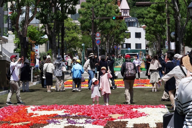 北野異人館街へ続く北野坂では３年ぶりにチューリップの花びらで描いた絵を並べたイベント「インフィオラータこうべ」が開かれた。大勢の観光客らでにぎわった＝４月３０日、神戸市中央区