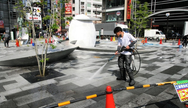 「さんきたアモーレ広場」の地面を洗浄する作業員＝神戸市中央区加納町４