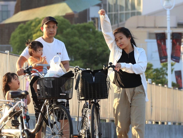 汗を拭うようなしぐさの女性＝２９日夕、神戸市中央区波止場町（撮影・吉田敦史）