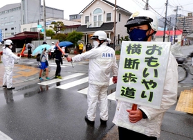 兵庫県警が指定した「おもいやり横断歩道」で横断歩道の歩行者優先を呼び掛ける警察官ら＝３月１８日、神戸市長田区細田町３
