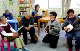 岩手県大槌町の仮設住宅を訪問し、沖縄の三線で交流する稲垣暁さん（右から２人目）＝２０１４年３月（提供写真）