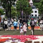 北野異人館街へ続く北野坂では３年ぶりにチューリップの花びらで描いた絵を並べたイベント「インフィオラータこうべ」が開かれた。大勢の観光客らでにぎわった＝４月３０日、神戸市中央区