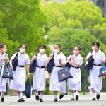 夏服のワンピースに身を包んで通学路を歩く生徒たち＝１６日朝、神戸市灘区王子町（撮影・秋山亮太）