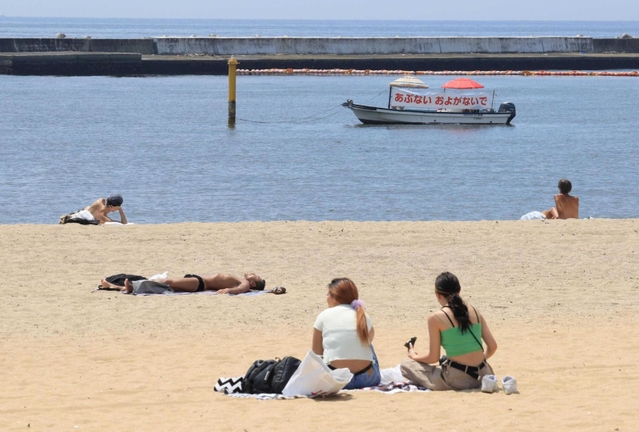 遊泳自粛中の海辺で日光浴などをする人たち＝２０２０年８月、神戸市須磨区、須磨海岸
