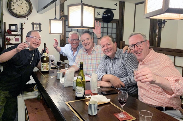コロナ禍の前、来店客との記念撮影に応じる松平寿史さん（左）。かつては外国人観光客が絶えなかった＝神戸市東灘区住吉宮町７（松平さん提供）
