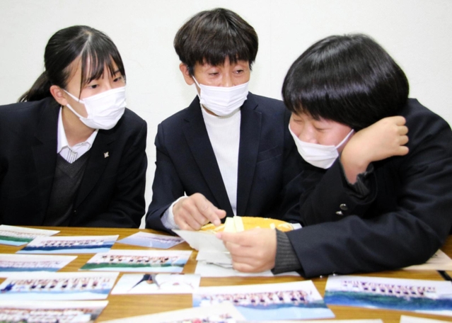 臨海学舎の写真を見ながら思い出話をする山瀬充子教諭（中央）と生徒たち＝西宮市学文殿町２、鳴尾高校