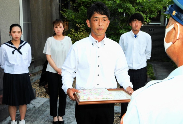 出火した車からけがをした４人を救助したとして、淡路広域消防事務組合の感謝状を受ける山田英輔さん（手前）と（後列左から）長女意寧さん、妻めぐみさん、長男臣之輔さん＝高砂市