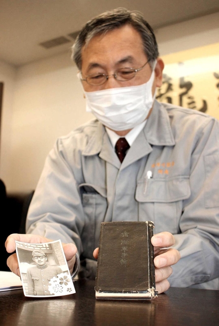 返還された手帳と戦死した岡崎梅太郎さんの写真を持つ孫の公一さん＝姫路市本町