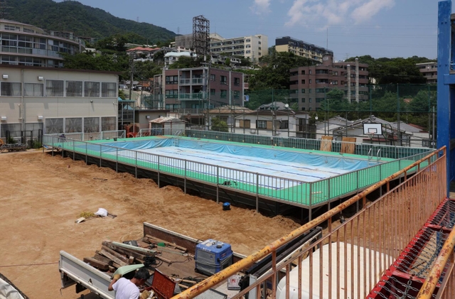 運動場いっぱいに設置されゆく仮設プール。３年ぶりの登場となる＝神戸市灘区箕岡通１、美野丘小学校（撮影・長嶺麻子）