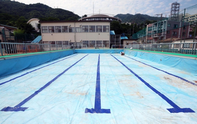 運動場いっぱいに設置されゆく仮設プール。３年ぶりの登場となる＝神戸市灘区箕岡通１、美野丘小学校（撮影・長嶺麻子）