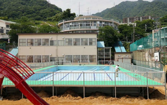 運動場いっぱいに設置されゆく仮設プール。３年ぶりの登場となる＝神戸市灘区箕岡通１、美野丘小学校（撮影・長嶺麻子）