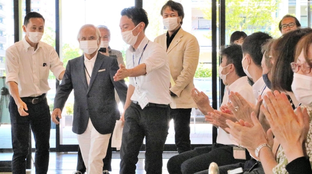 古野電気の社員に拍手で迎えられる堀江謙一さん（左から２人目）＝西宮市芦原町９、古野電気