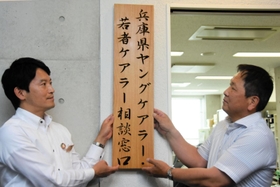 専門相談窓口の看板を掲げる斎藤元彦知事（左）と谷口弘会長＝神戸市中央区坂口通２