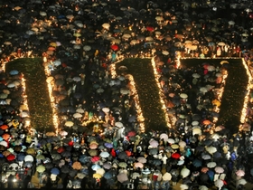 震災発生から１０年。「１・１７」の灯り文字を大勢の傘の花が取り囲んだ＝２００５年１月１７日午前５時４６分、神戸・三宮の東遊園地