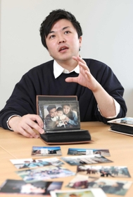 幼い自分を抱く両親の写真を手に、歩みを振り返る中村翼さん＝神戸市中央区東川崎町１（撮影・小林良多）