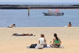 遊泳自粛中の海辺で日光浴などをする人たち＝２０２０年８月、神戸市須磨区、須磨海岸