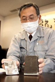 返還された手帳と戦死した岡崎梅太郎さんの写真を持つ孫の公一さん＝姫路市本町