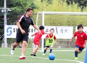 斎藤元彦知事が視察する中、子どもたちと笑顔でサッカーを楽しむ岡崎慎司選手＝神戸市西区平野町印路