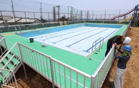 運動場いっぱいに設置されゆく仮設プール。３年ぶりの登場となる＝神戸市灘区箕岡通１、美野丘小学校（撮影・長嶺麻子）