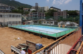 運動場いっぱいに設置されゆく仮設プール。３年ぶりの登場となる＝神戸市灘区箕岡通１、美野丘小学校（撮影・長嶺麻子）