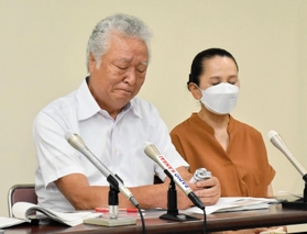 悔しさで唇をかむ木戸一仁さん（左）と妻久美子さん＝２２日午後、神戸市中央区橘通３、市立婦人会館