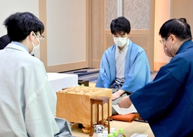 立会人の小林健二・九段（右）から封じ手を示される藤井聡太王位。左は豊島将之九段＝２９日午前、愛知県犬山市、ホテルインディゴ犬山有楽苑