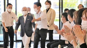 古野電気の社員に拍手で迎えられる堀江謙一さん（左から２人目）＝西宮市芦原町９、古野電気