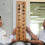 専門相談窓口の看板を掲げる斎藤元彦知事（左）と谷口弘会長＝神戸市中央区坂口通２